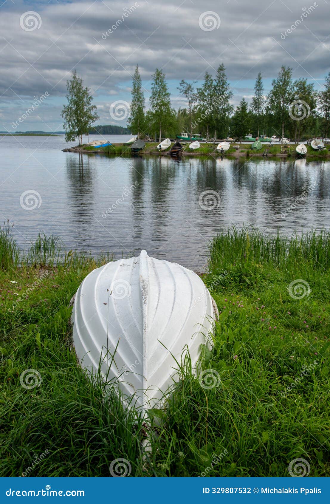 one white rowboat moored near reed grass on lake during a cloudy day