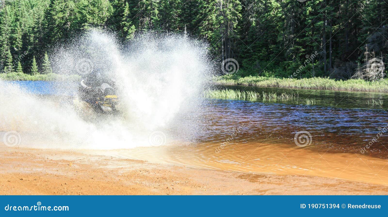 man driving motocross atv quad through splashing river lake water with high speed. foy, foyross lake, sudbury, canada.
