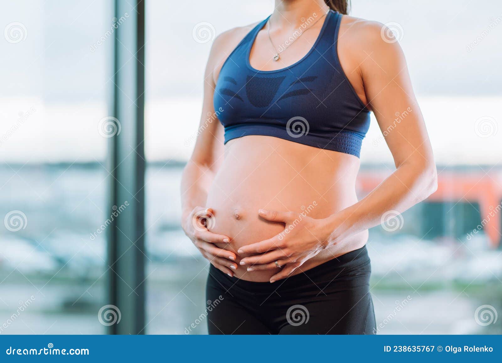 Executie zien Vertolking Onherkenbare Zwangere Vrouw in Sportkleding Met Ketting En Hanger Op De Nek  Die De Buik Tegen De Achtergrond Van Het Raam Aandoet. Stock Afbeelding -  Image of levensstijl, buik: 238635767