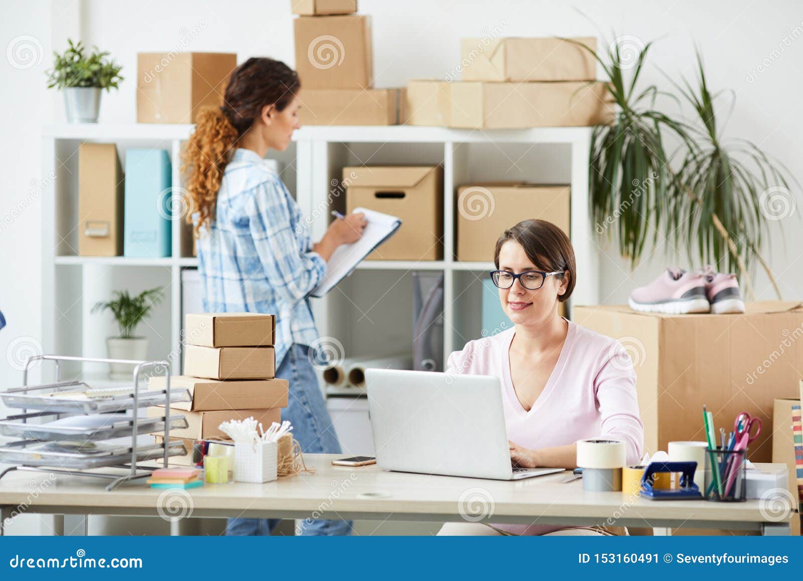 Online Shop Office Manager Networking while Her Colleague Making Notes