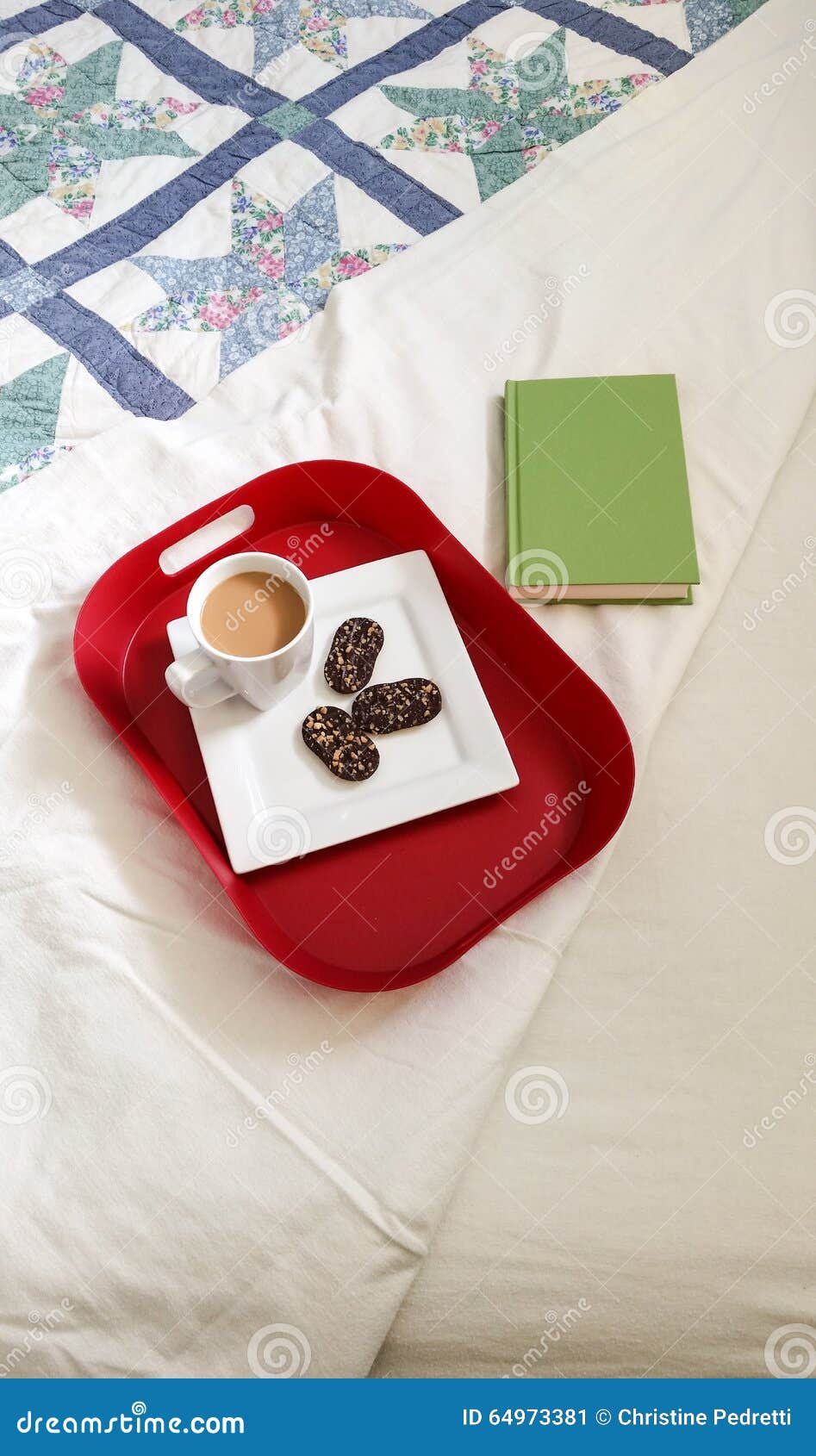 Ontbijt in bed. Rood dienblad met witte plaat en mok op bed met lapwerkdekbed