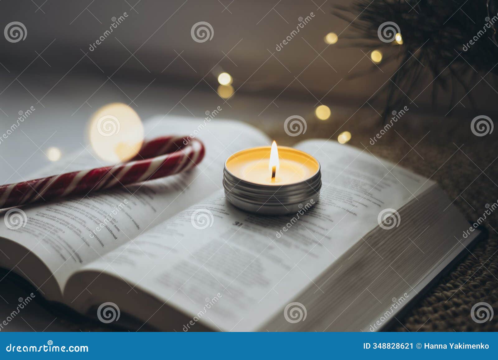 open bible, burning candle and christmas candy on the windowsill at home.