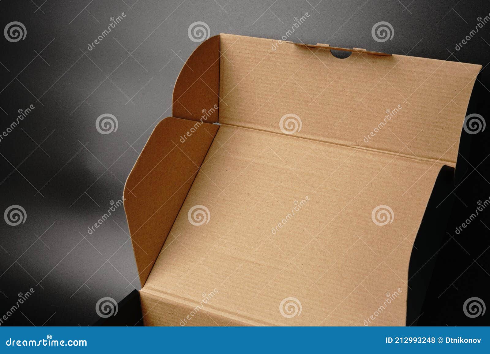 An Open Cardboard Box on a Black Background. Dimmed Lights Stock Photo