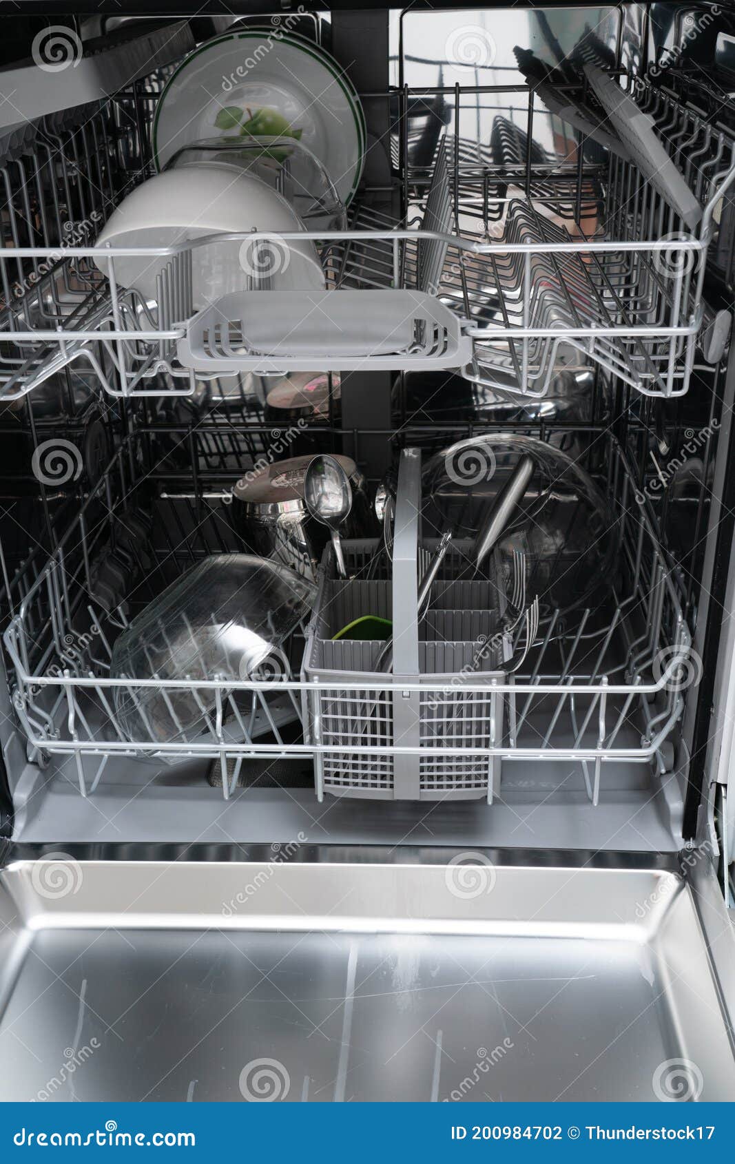 open dishwasher with cutlery and plates as domestic appliance