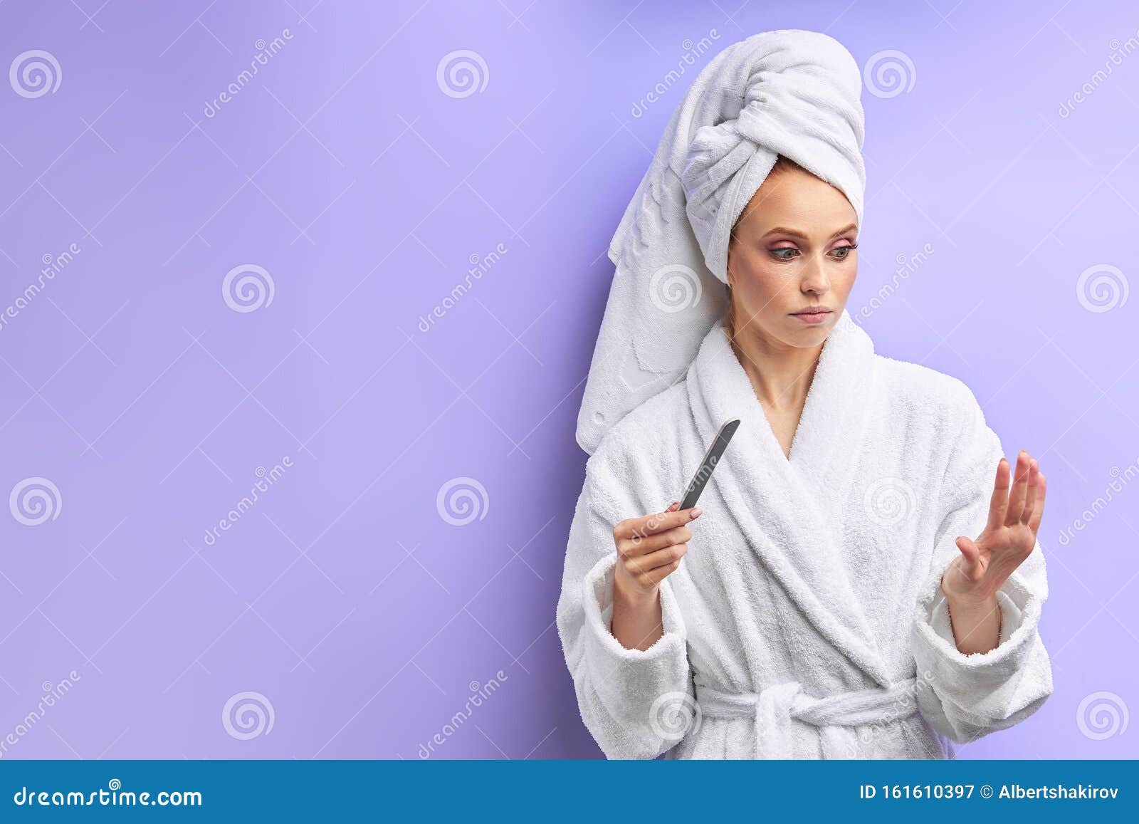young women in bathrobe trimming nails with nailfile