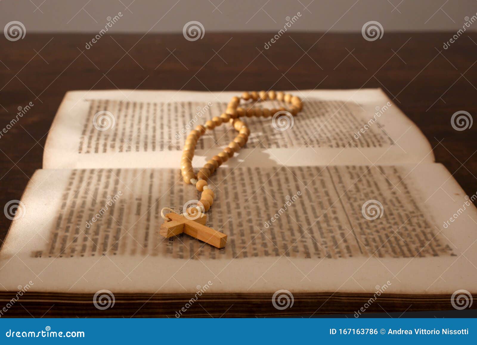 Open Holy Bible And A Cross With Rosary Rest On A Wooden Table