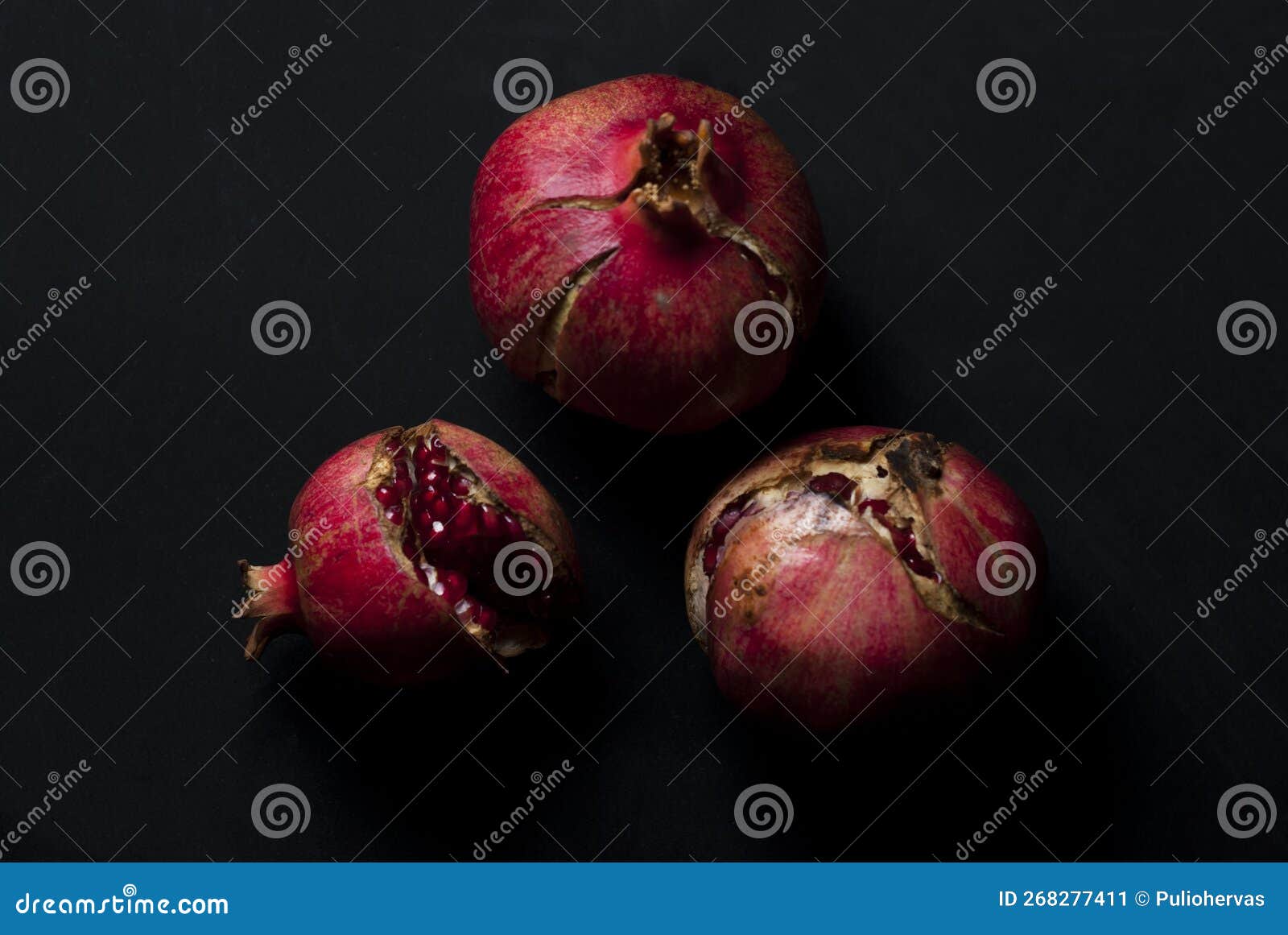 open red ripe pomegranates ready to eat on a black background overhead view
