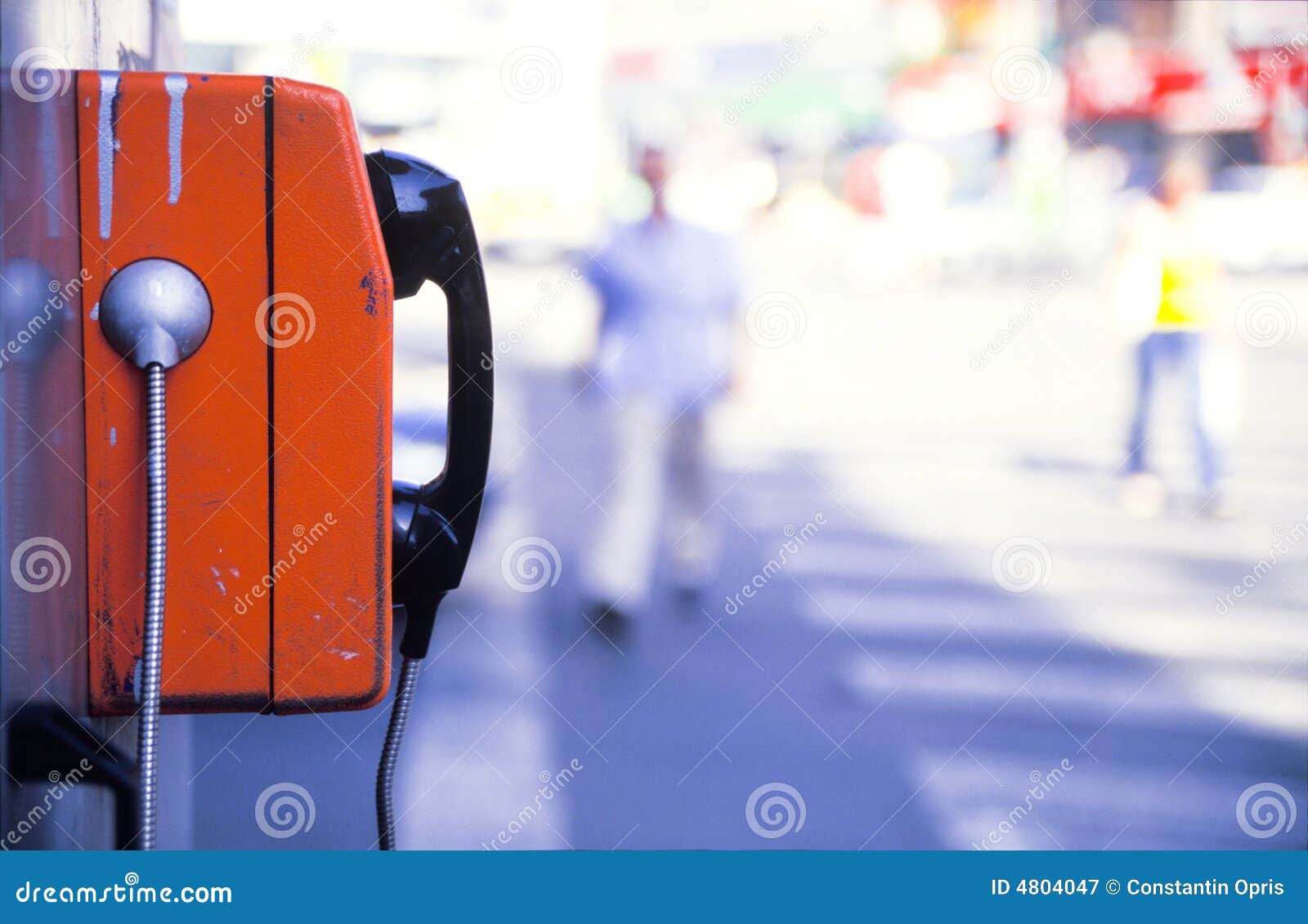 Een oranje openbare telefoon op een straat.