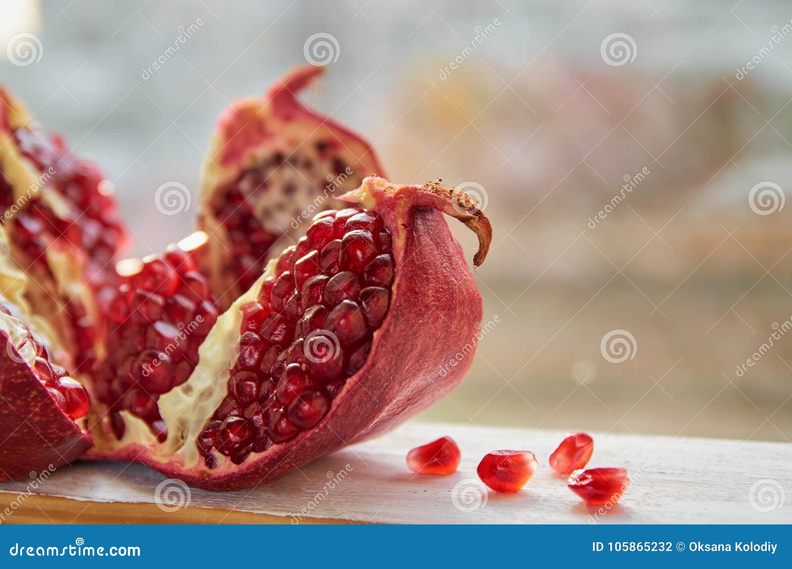 opened big red pomegranate on the white wooden table. pieses of juice pomegranate with seeds on the blurred nature background