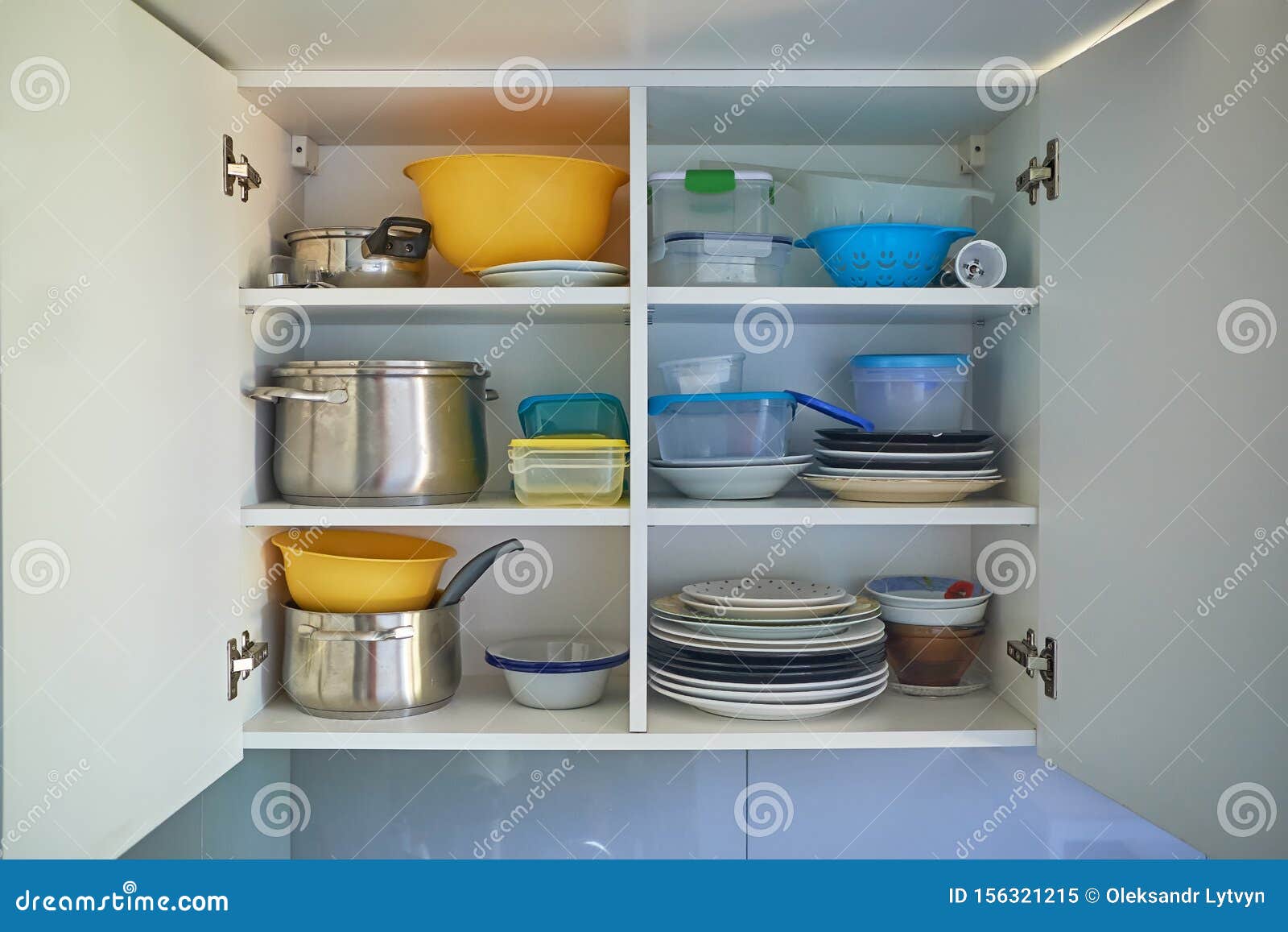 Opened White Kitchen Cupboard With Plates Metal Pots And Food