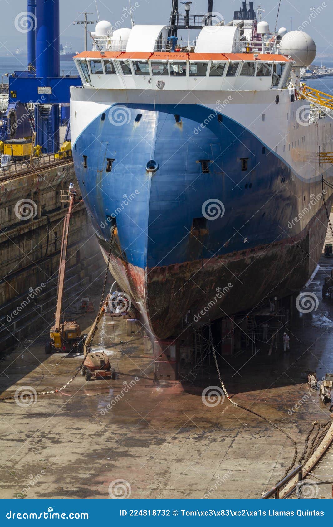 workers cleaning the hull of a merchant ship in the dry dock