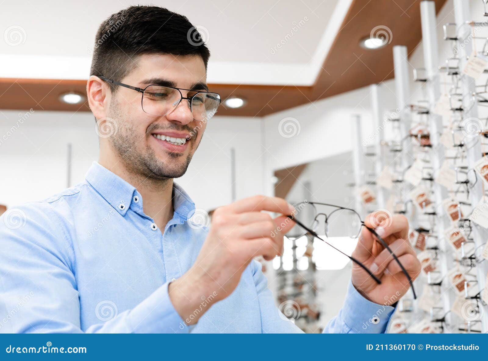 Portrait of Happy Young Male Customer Choosing Eyeglasses Stock Photo ...