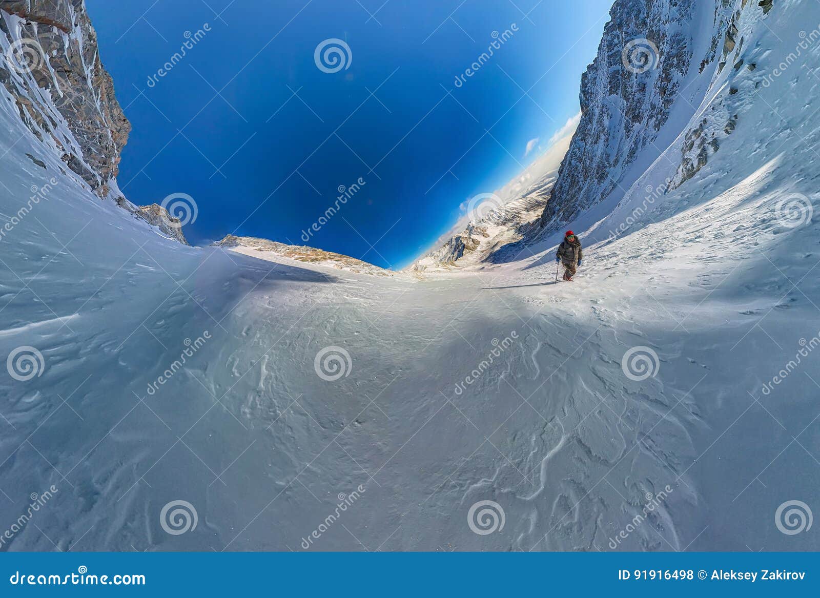 Opinião de ângulo larga um caminhante da montanha para escalar uma montanha do couloir da neve