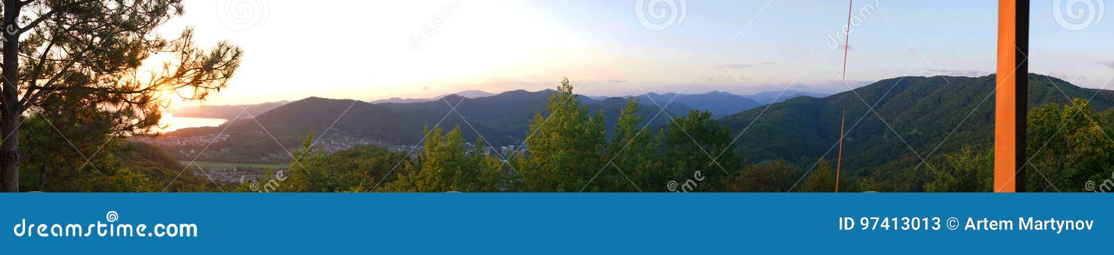 Opinión colorida panorámica hermosa de la puesta del sol sobre el Mar Negro y las montañas Agoy, región de Tuapse Rusia. Paisaje colorido panorámico hermoso de la tarde de la opinión de la bahía de la montaña y del mar Costee la línea del Mar Negro en el amanecer con una puesta del sol anaranjada pintoresca al lado del árbol de pino Agoy, región de Tuapse, Rusia