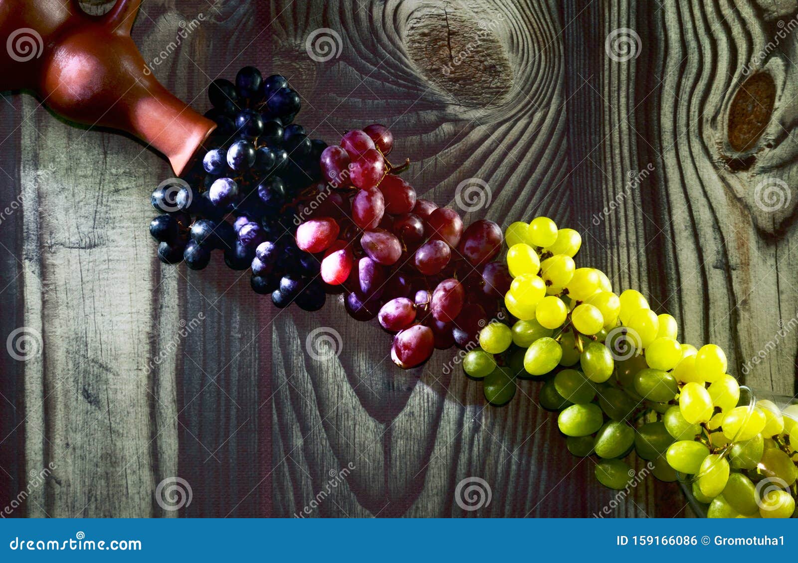 opposite the clay wine bottle are grapes of chardonnay, traminer and isabella for the production of dessert wines. the clusters