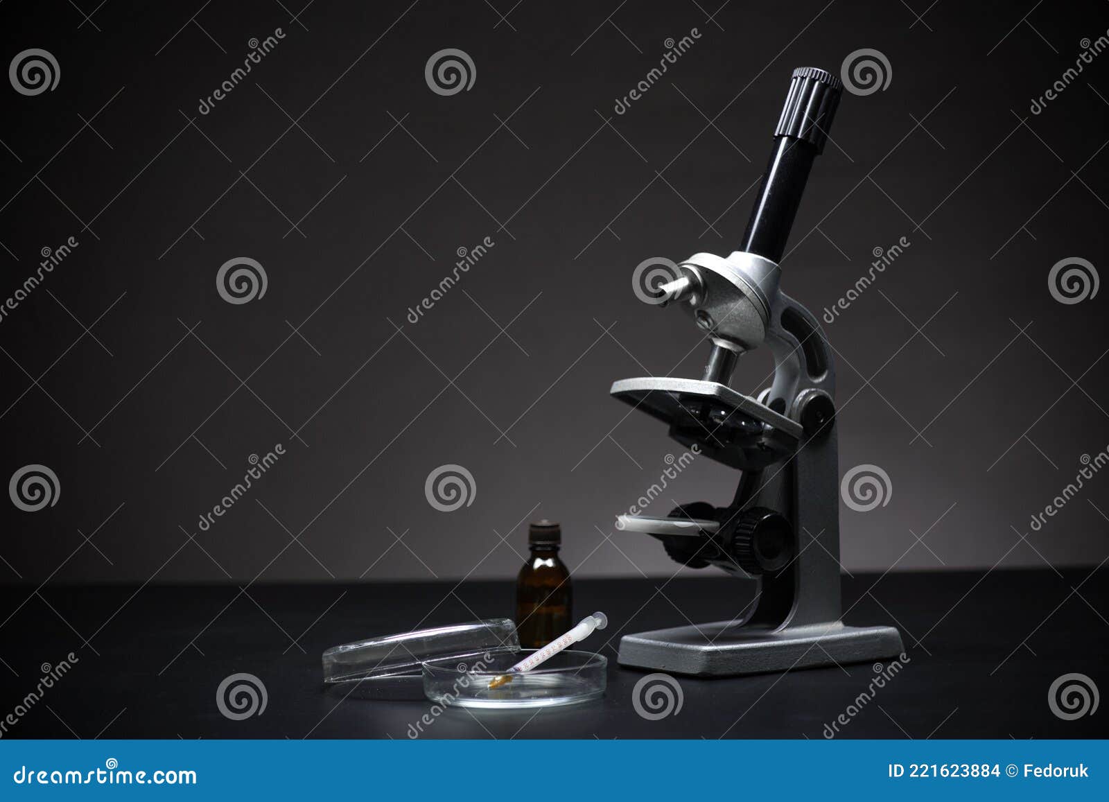 Optical Microscope on a Black Background, Petri Dish and Syringe for