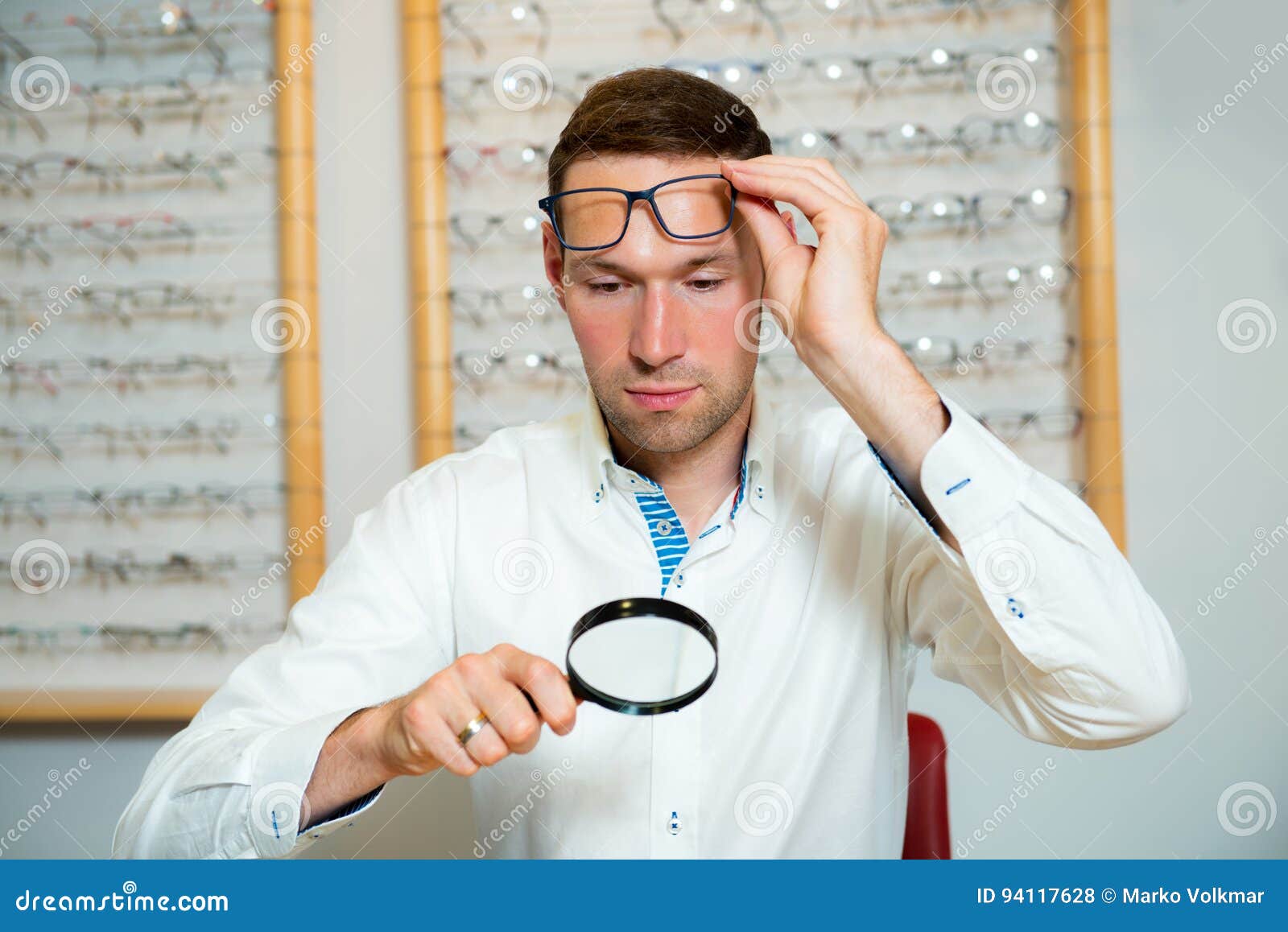 In Optician Shop- Young Man with Magnifier Selecting New Reading Stock ...