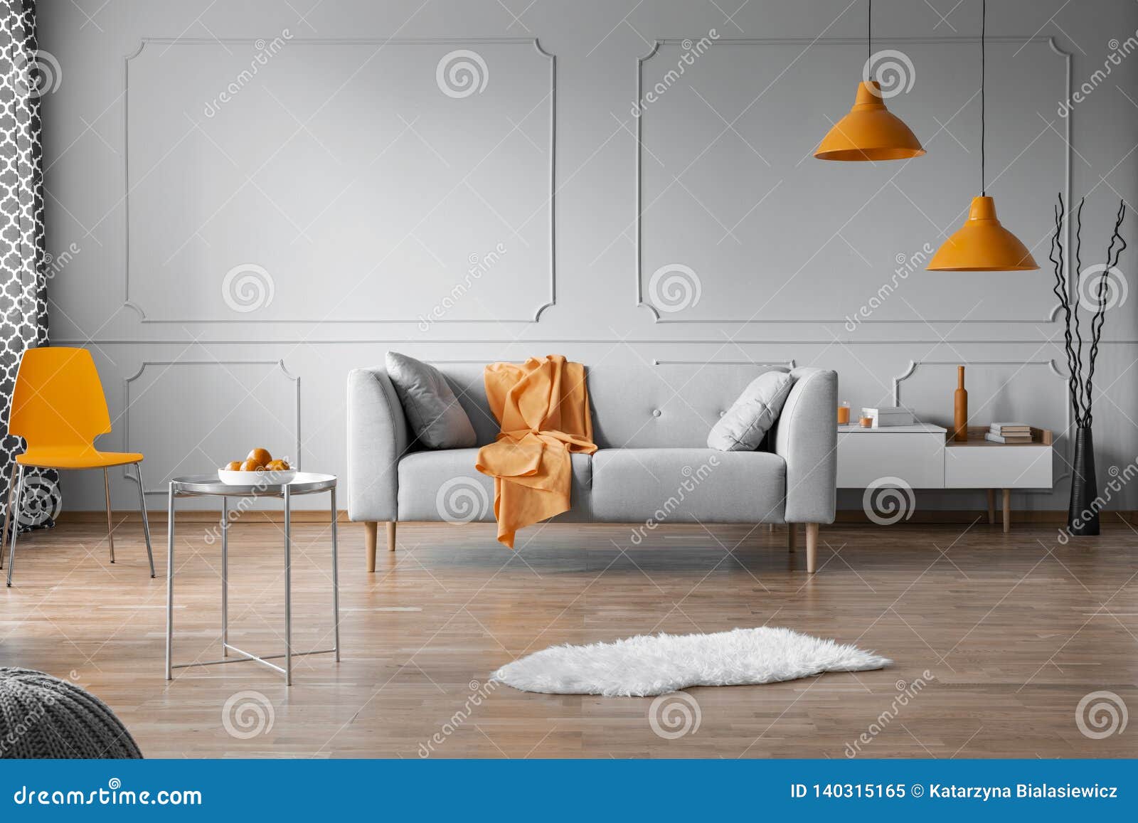 orange accents in grey living room interior with copy space on empty wall