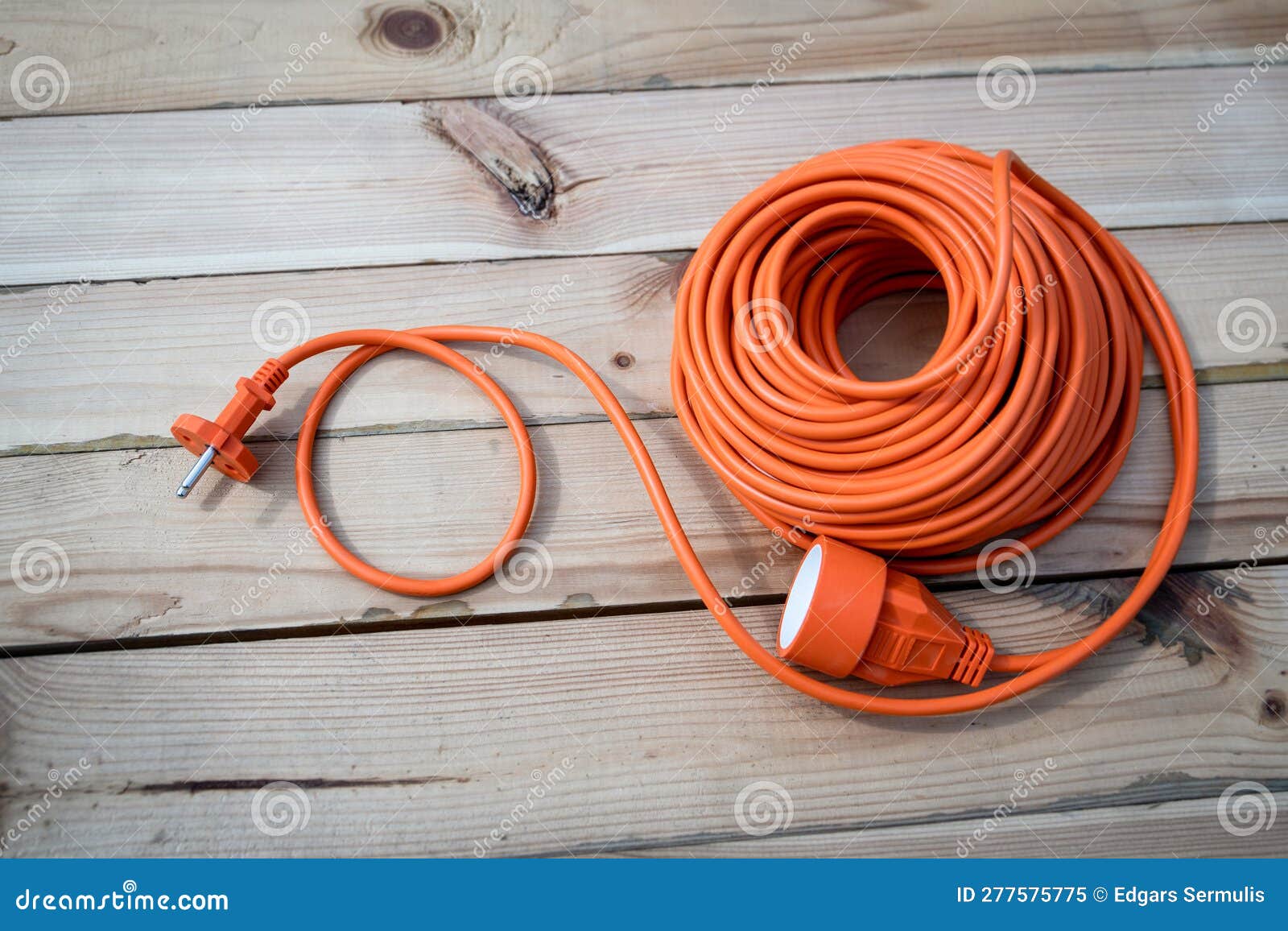 Orange Construction Electrical Extension Cord Coiled on Wood Texture