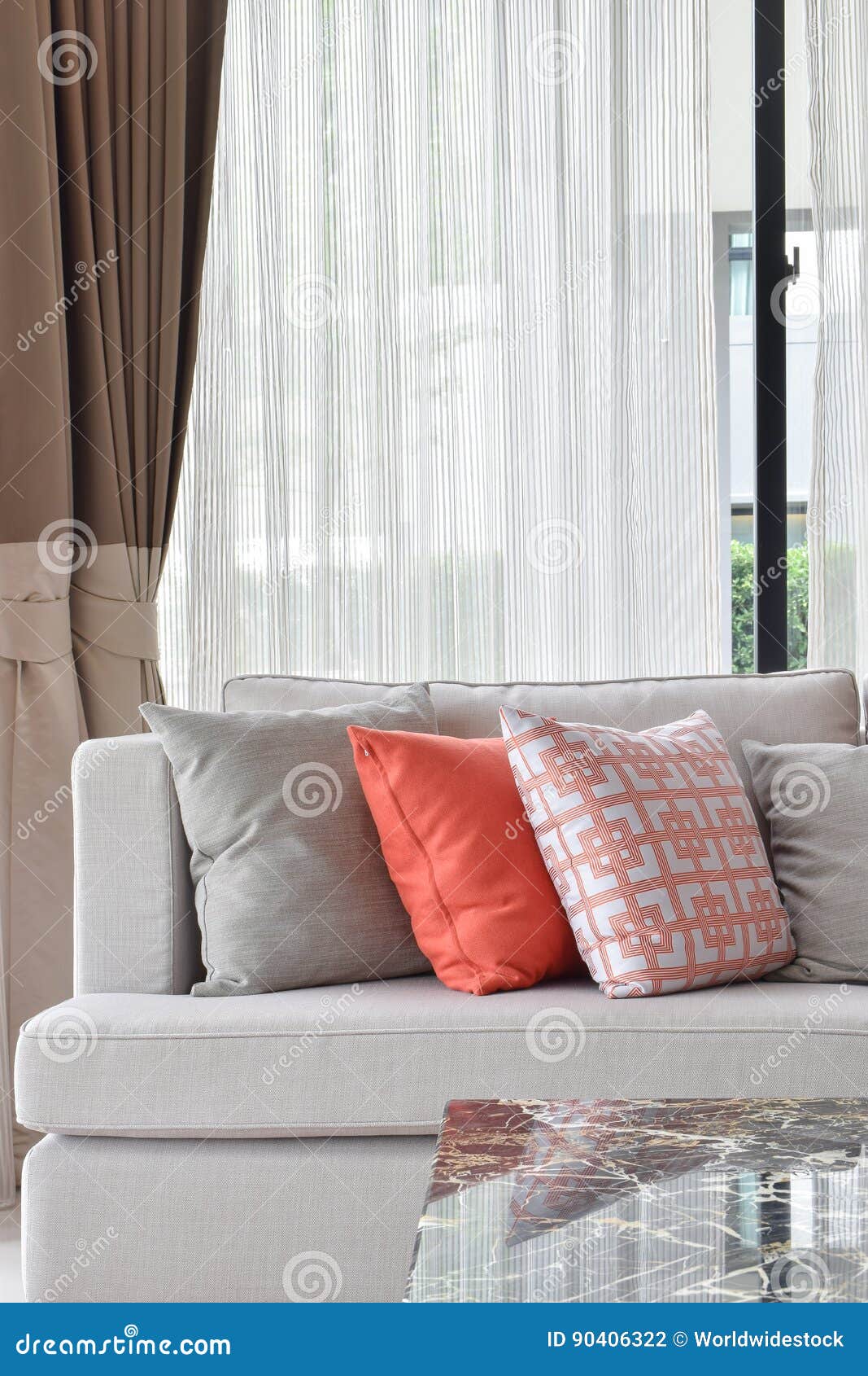 Orange and Gray Pillows Setting on Beige Sofa in Cozy Living Room Stock