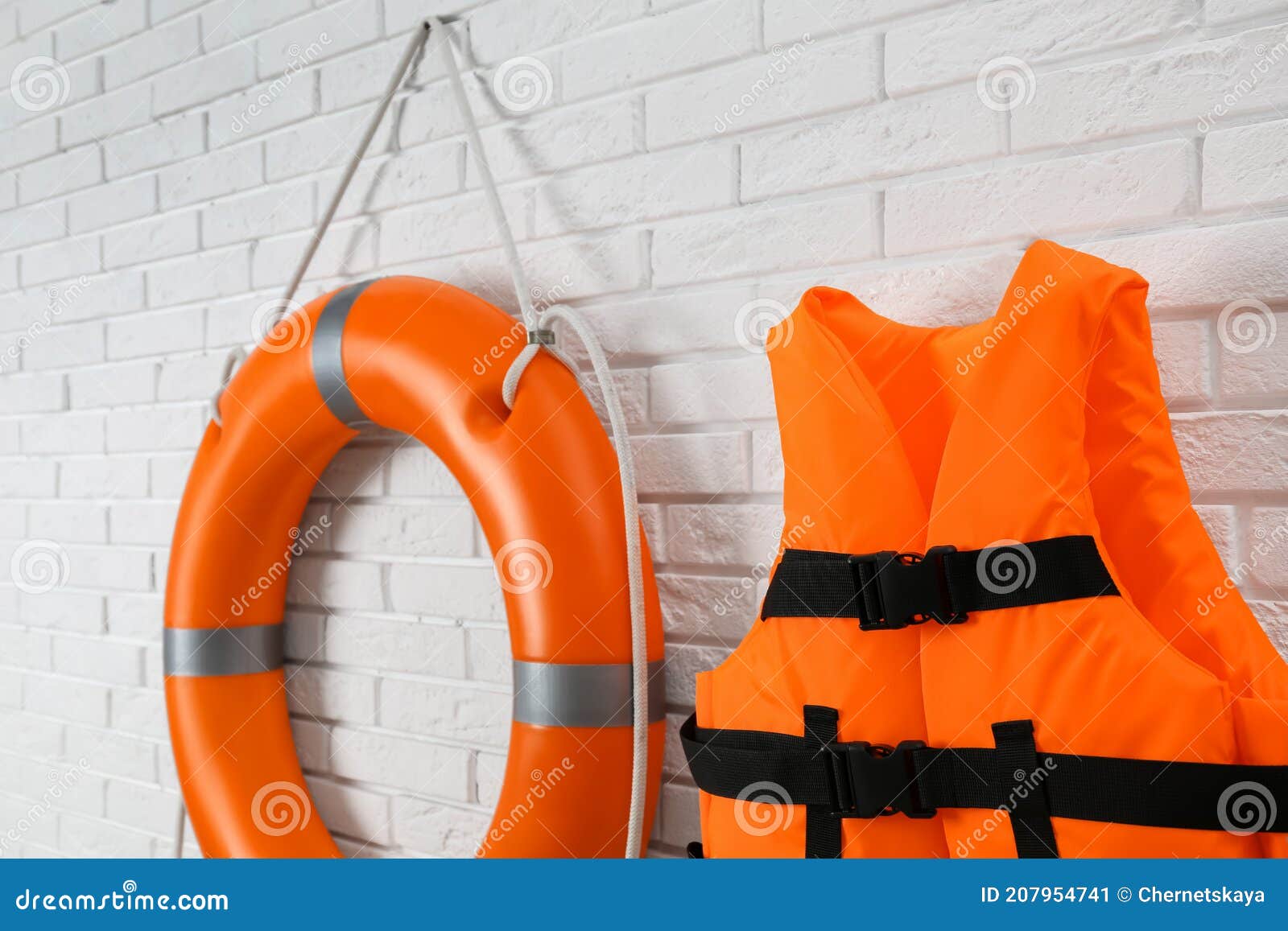 Orange Life Jacket and Lifebuoy on White Brick Wall. Rescue Equipment ...