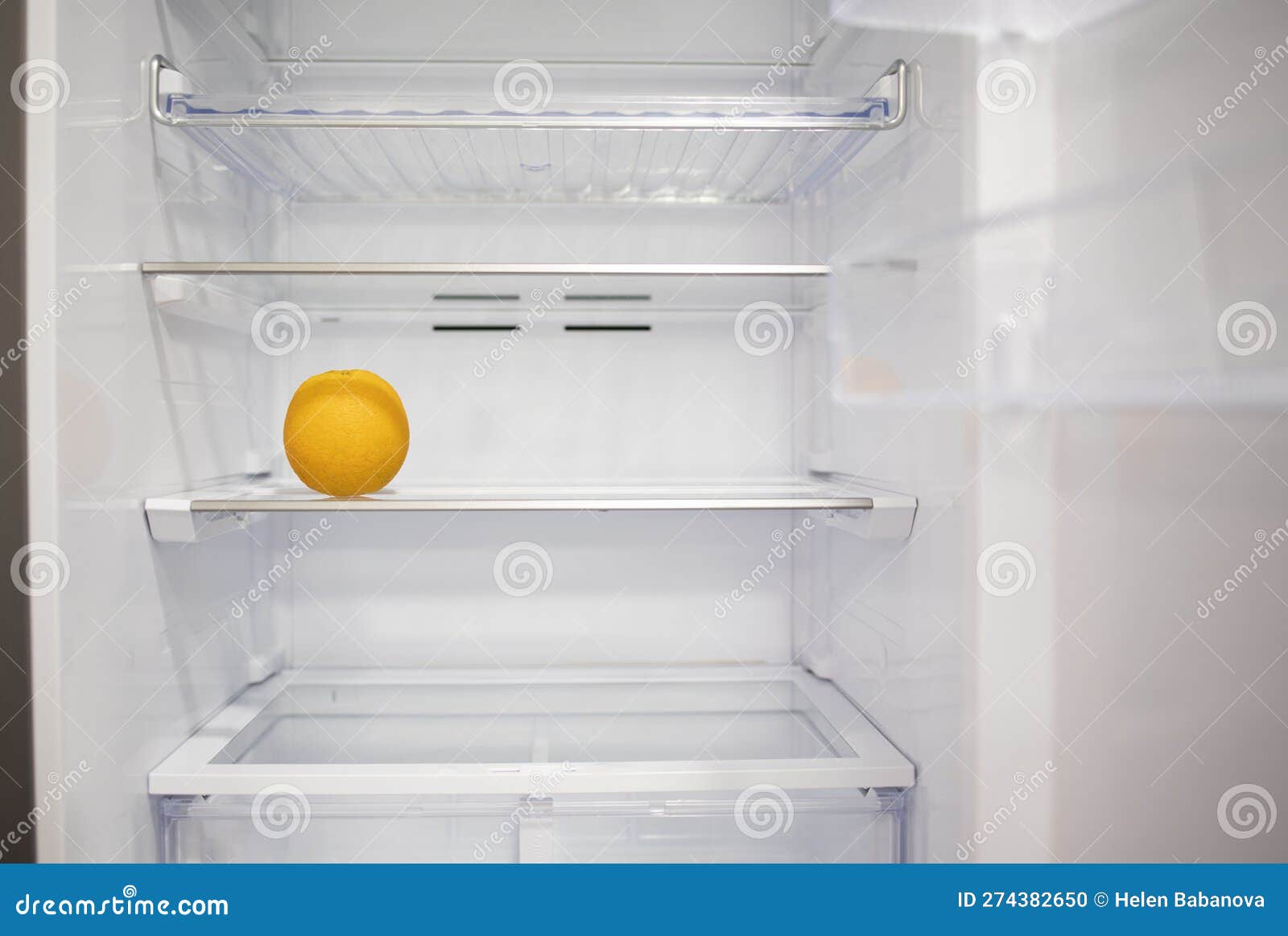 Orange Lying Against the Background of a White Empty Fridge Shelf Stock