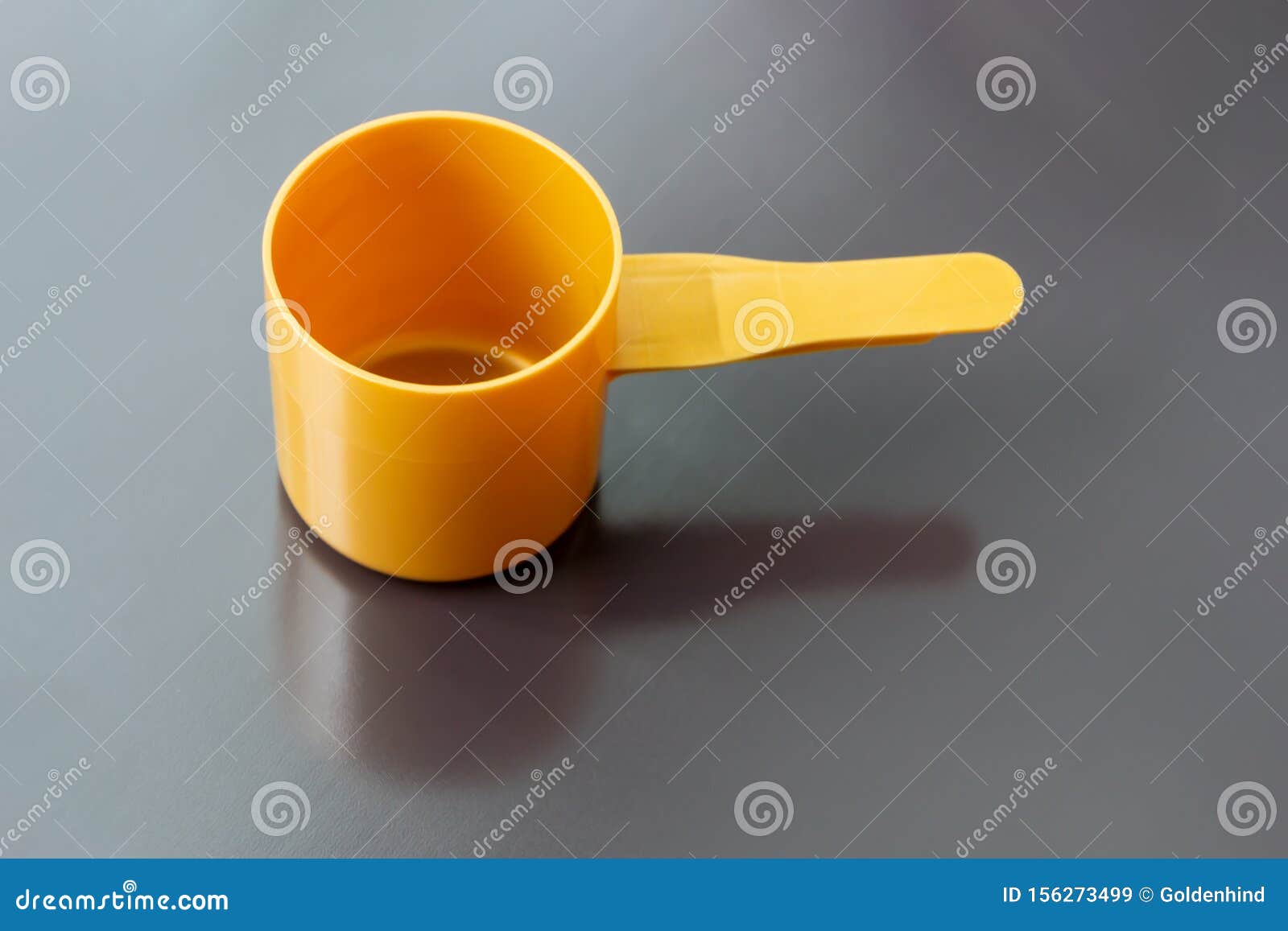 orange plastic measuring dosage spoon on dark background