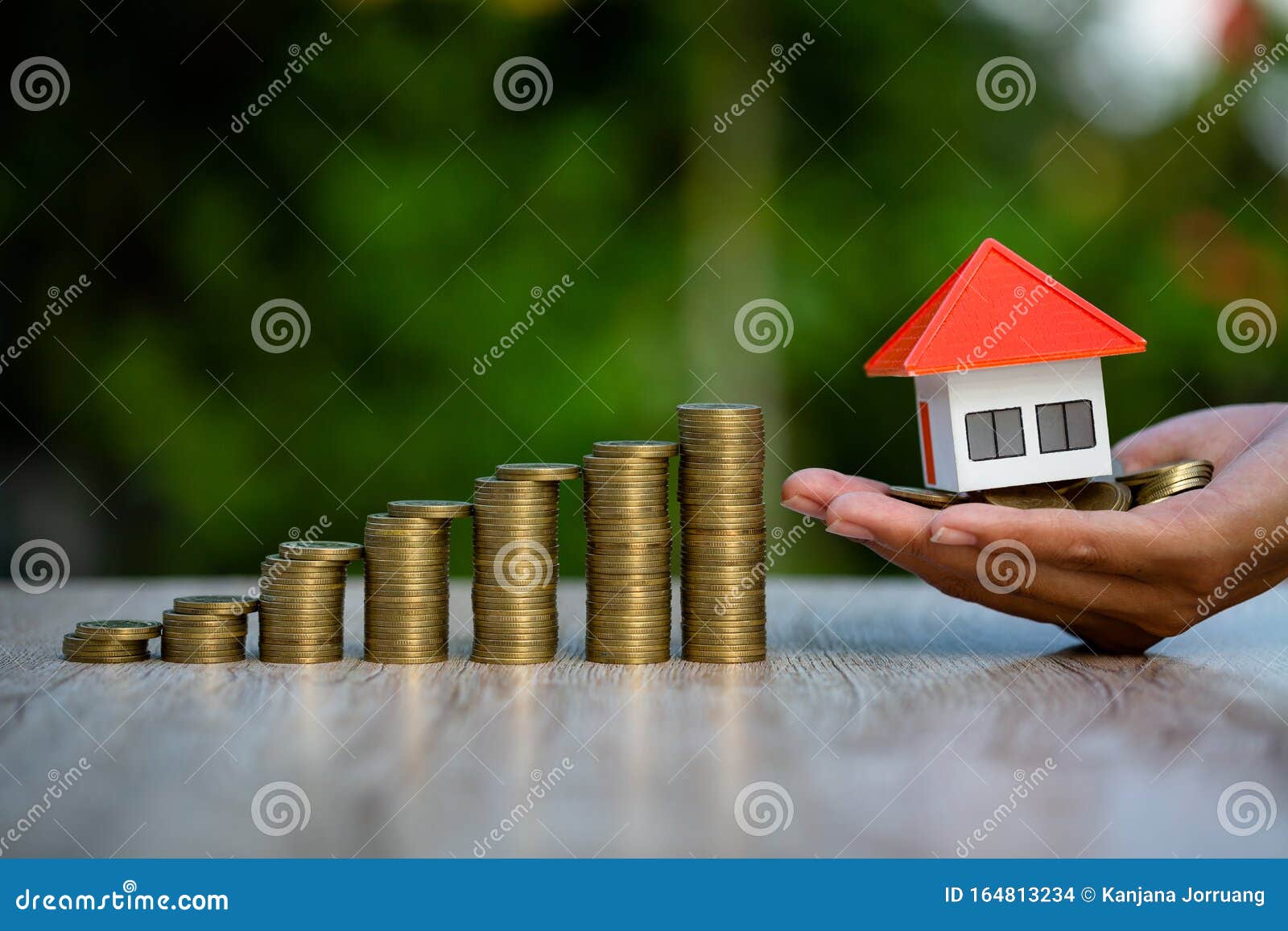orange roof house in investor`s hand placed close to the medallion, increasing the number of coins. real estate investment concep