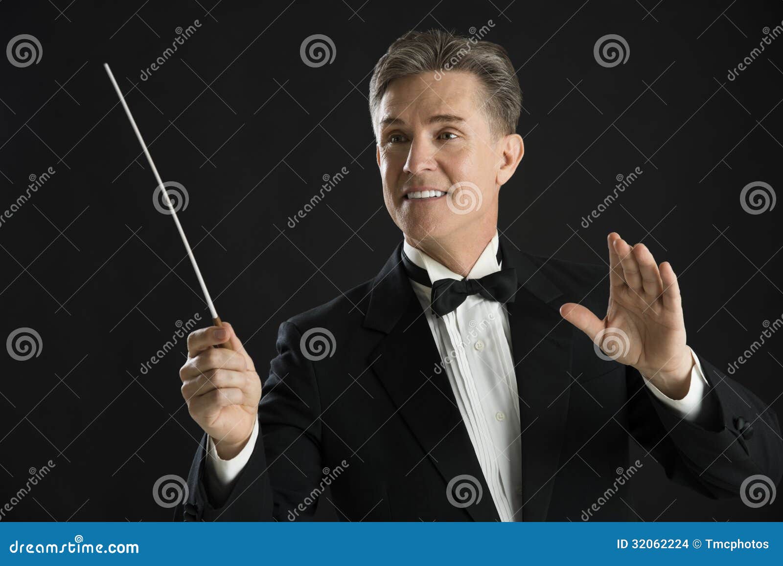 orchestra conductor looking away while directing with his baton