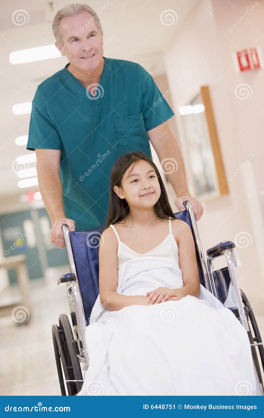 an orderly pushing a little girl in a wheelchair
