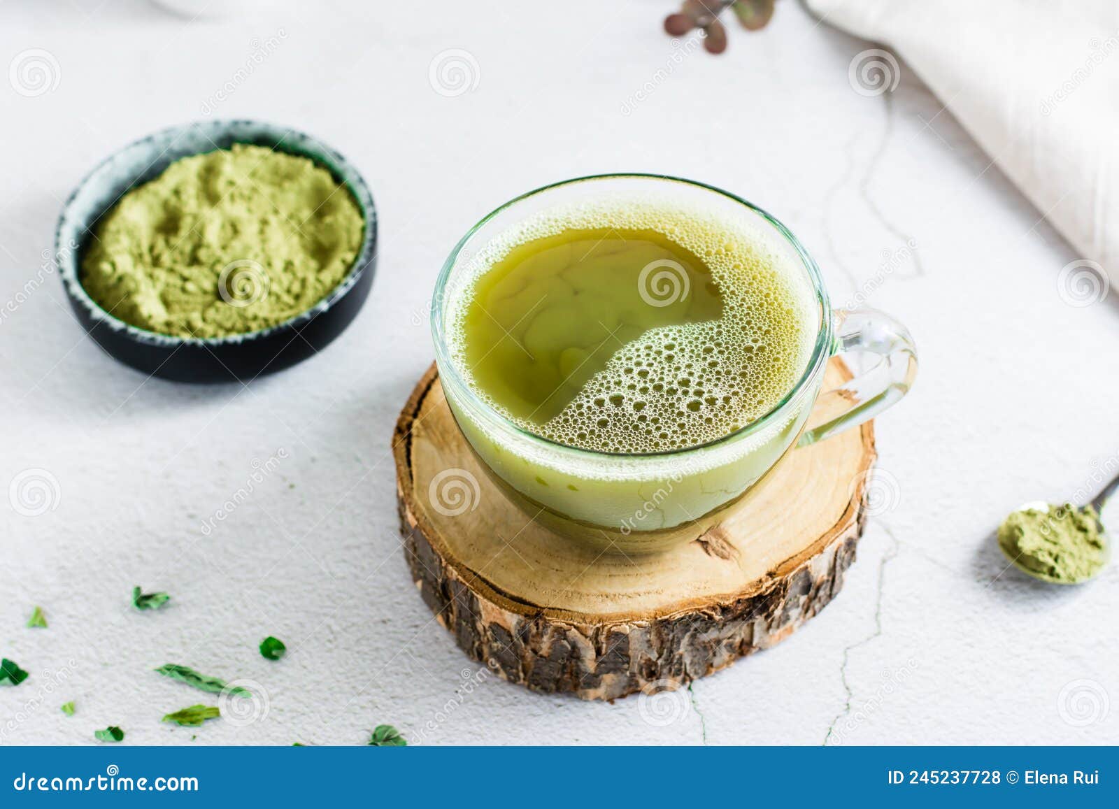 Organic Green Matcha Tea in a Cup on a Tree Trunk on the Table. Close