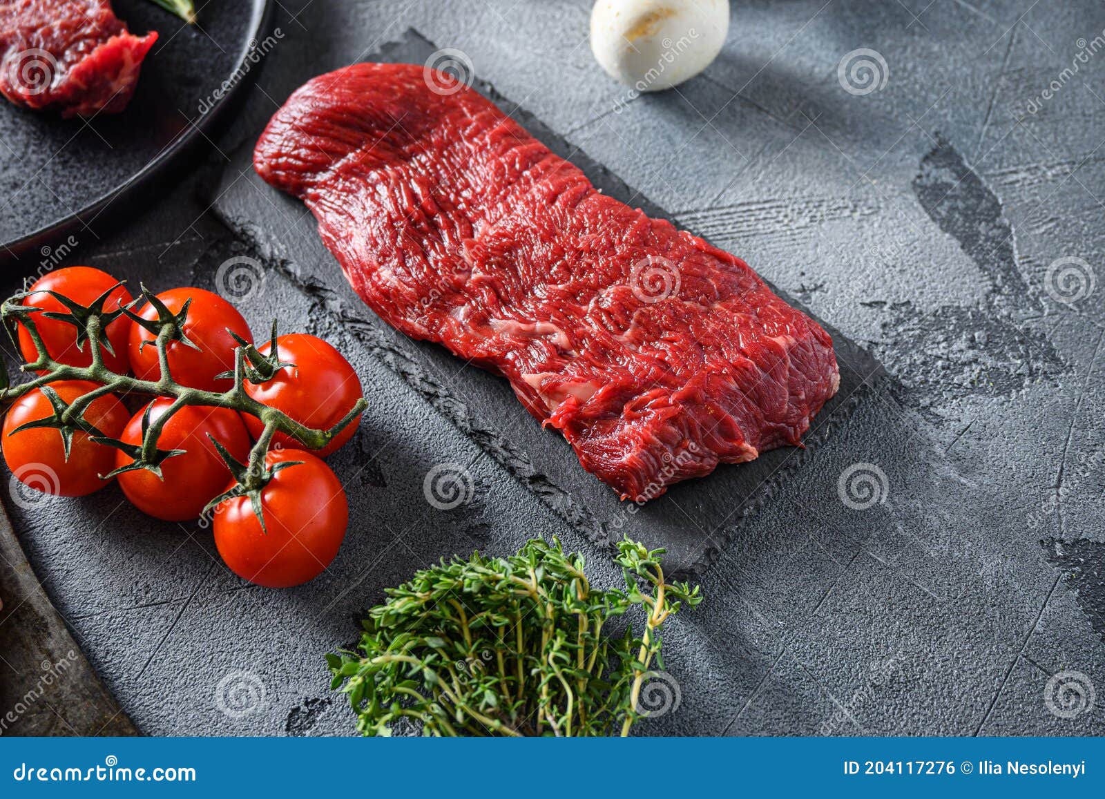 organic tri tip, triangle  roast cut steak on black  slate raw meat , marbled beef over other alternative cuts  with herbs