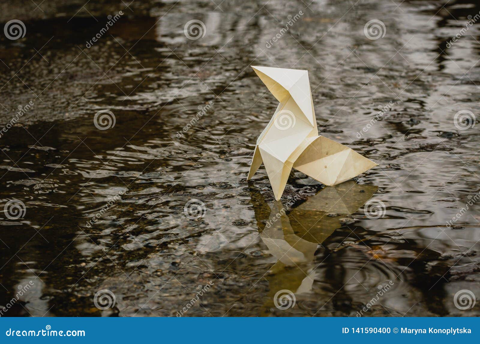 origami paper figure on the background of a gloomy city street and puddles