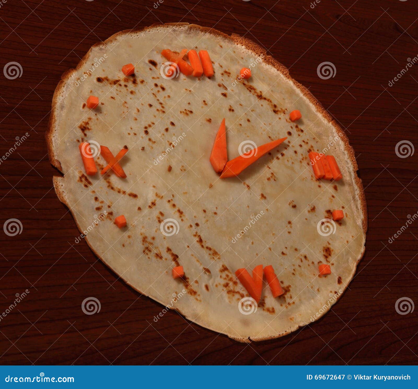 Orologio commestibile dalla carota e dal pancake su fondo di legno