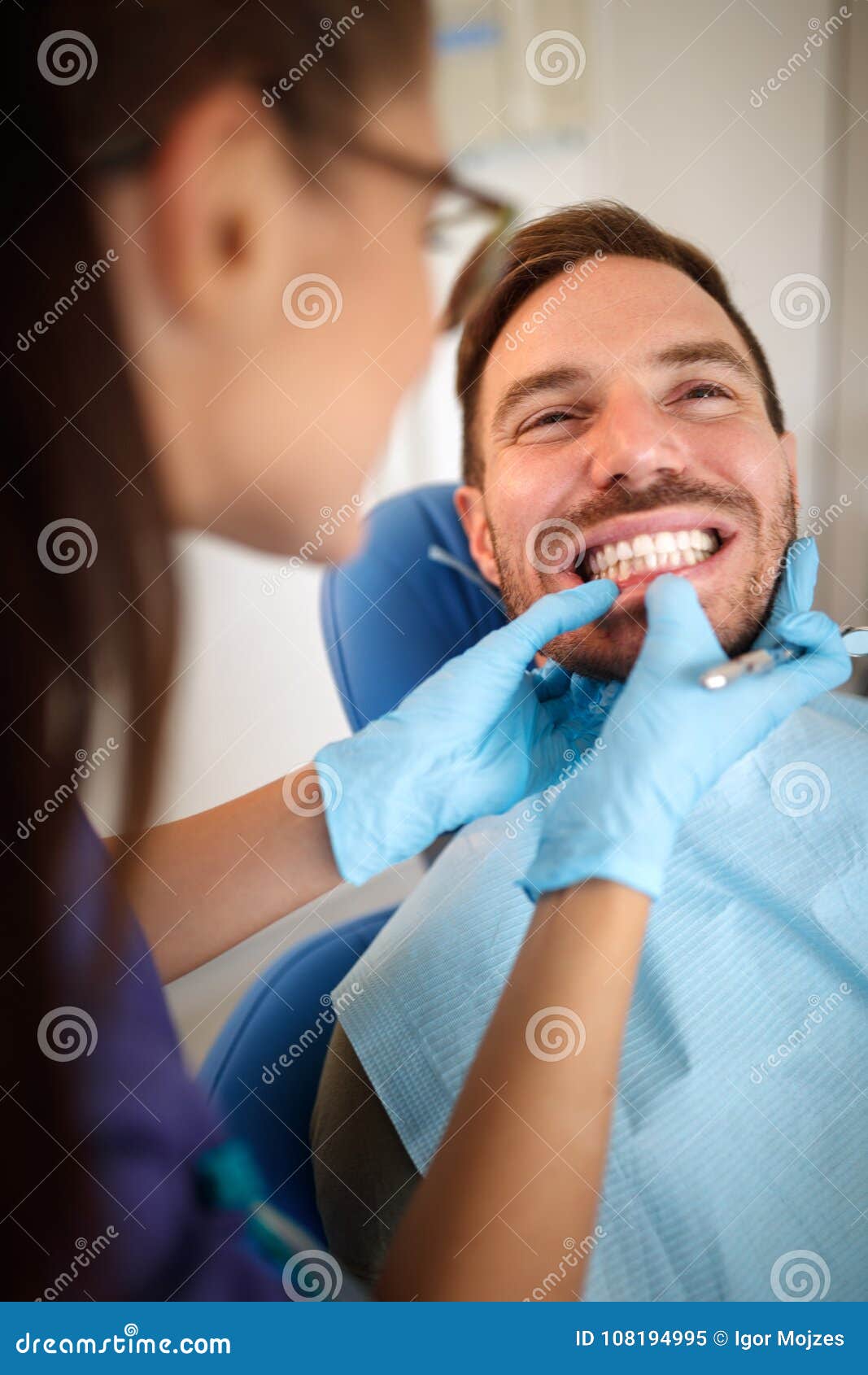 orthodontist in dental clinic looking patient`s bite