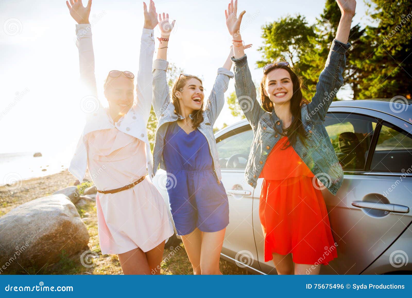 Os adolescentes ou as mulheres felizes aproximam o carro no beira-mar. Férias de verão, feriados, curso, viagem por estrada e conceito dos povos - os adolescentes ou as jovens mulheres felizes aproximam o carro no beira-mar