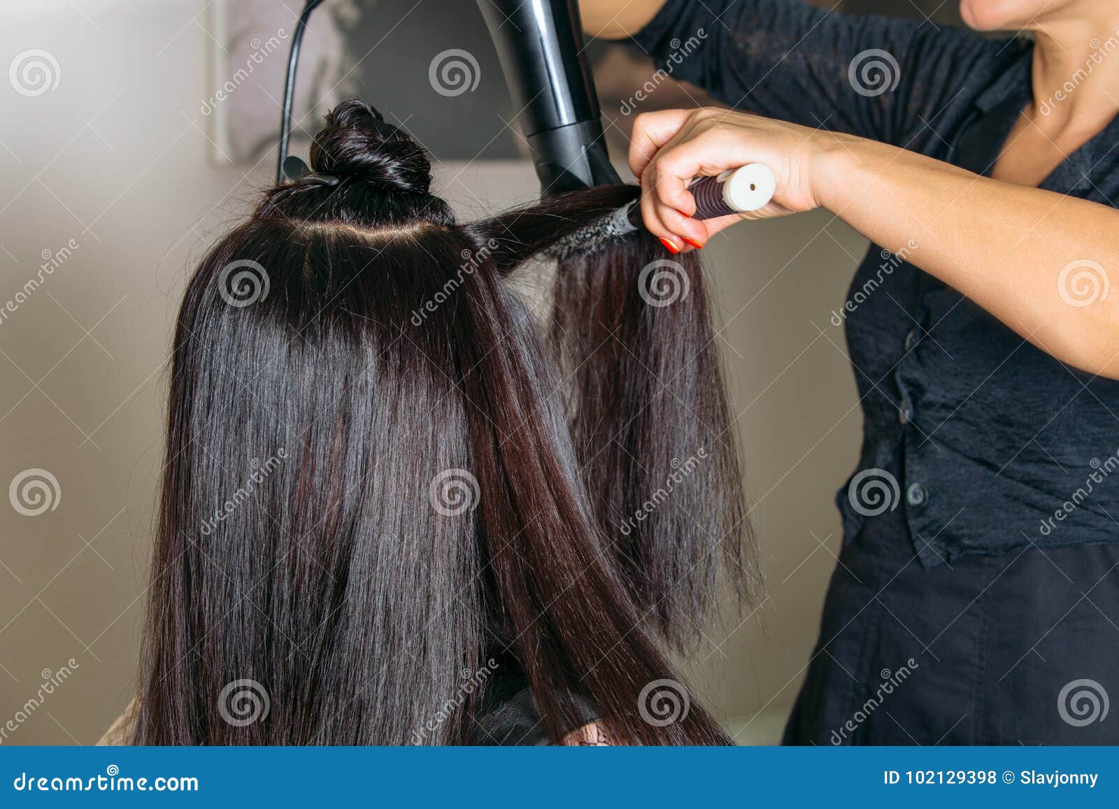 O cabeleireiro usa um secador de cabelo e modela o cabelo de uma