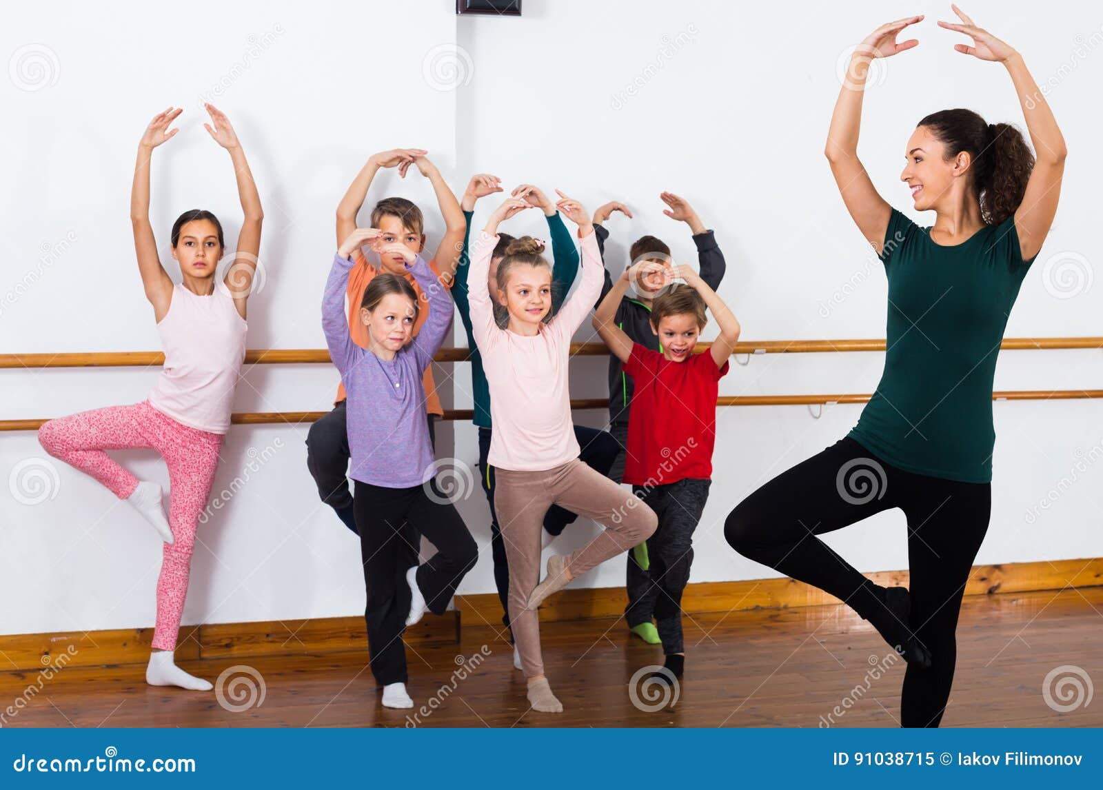 Os meninos concentrados e as meninas que ensaiam o bailado dançam no estúdio. Idade de escola primária concentrada dos meninos e das meninas que ensaia a dança do bailado no estúdio