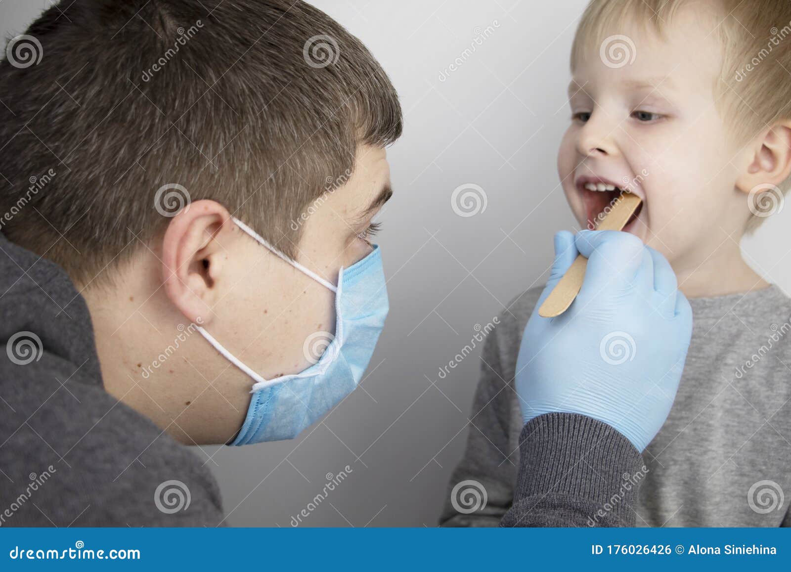 an otolaryngologist examines a child`s throat with a wooden spatula. a possible diagnosis is inflammation of the pharynx, tonsils