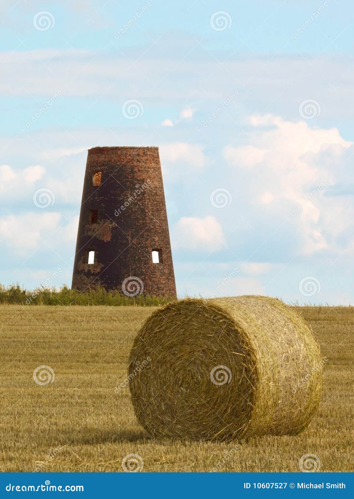 Een oude windmolen binnen ver weg van ronde balen in oogsttijd in de zomer