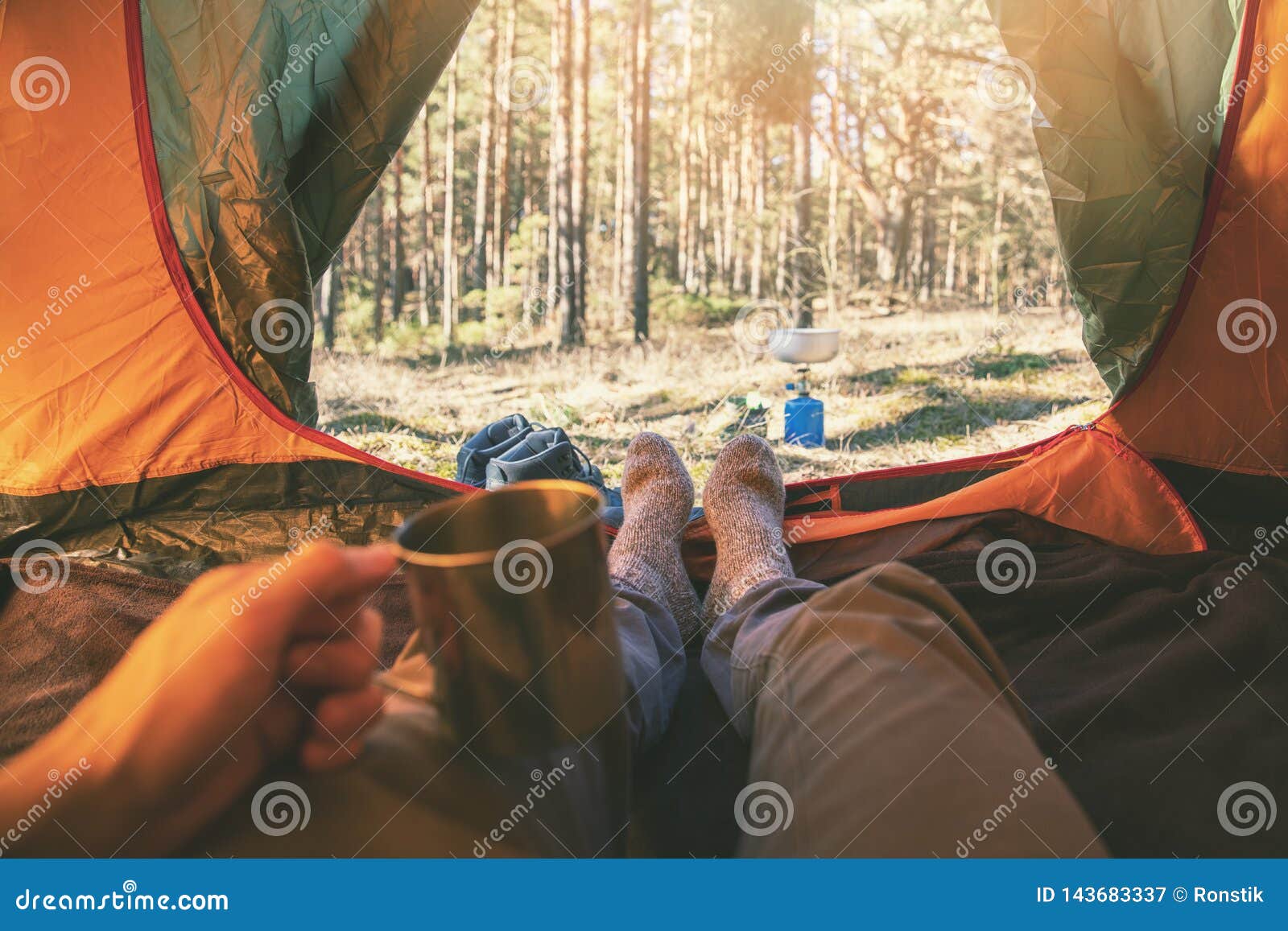 outdoor adventure tourism - man laying in tent with cup of tea