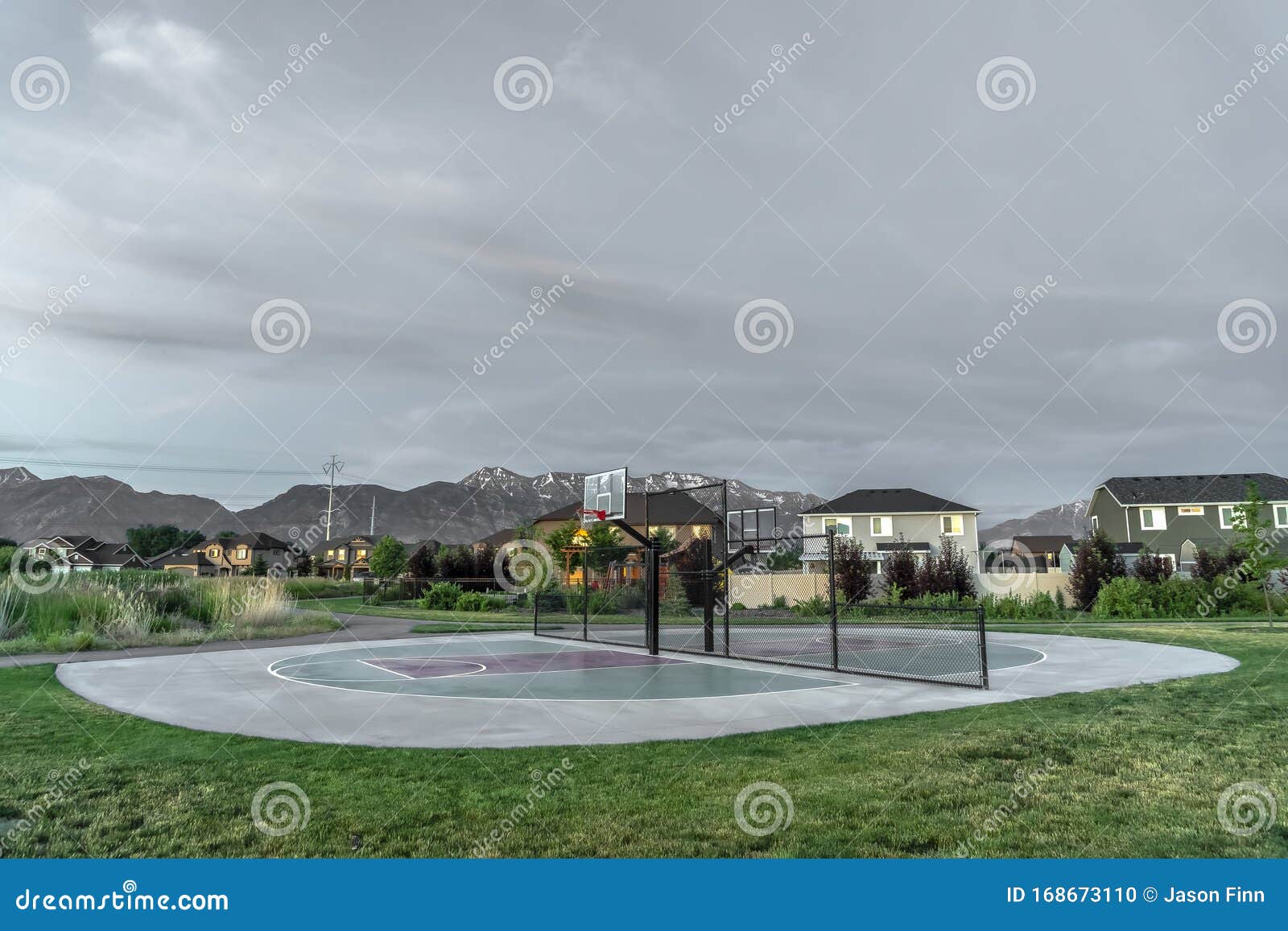 Outdoor Basketball Court with Homes and Mountain Against Overcast