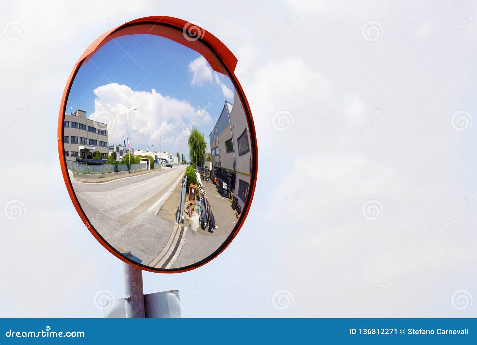 outdoor convex safety mirror hanging on wall with reflection of an urban roadside view of cars parked along the street