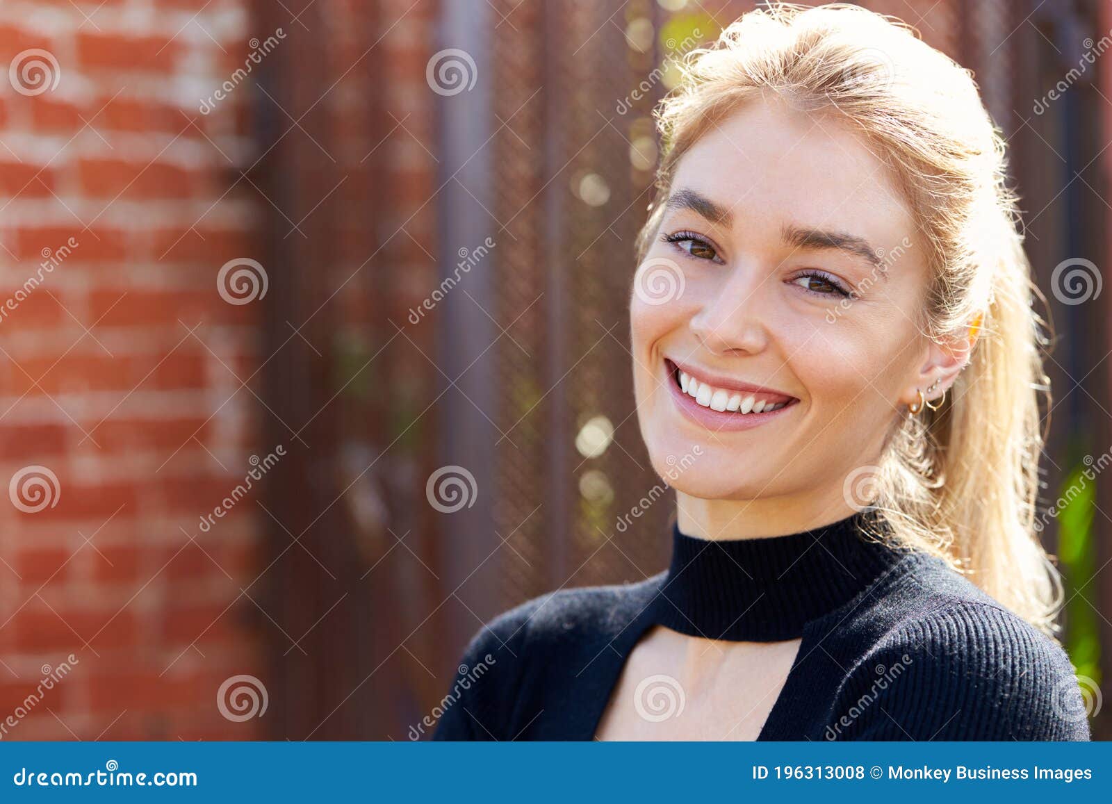 outdoor head and shoulders portrait of attractive young woman standing in the street