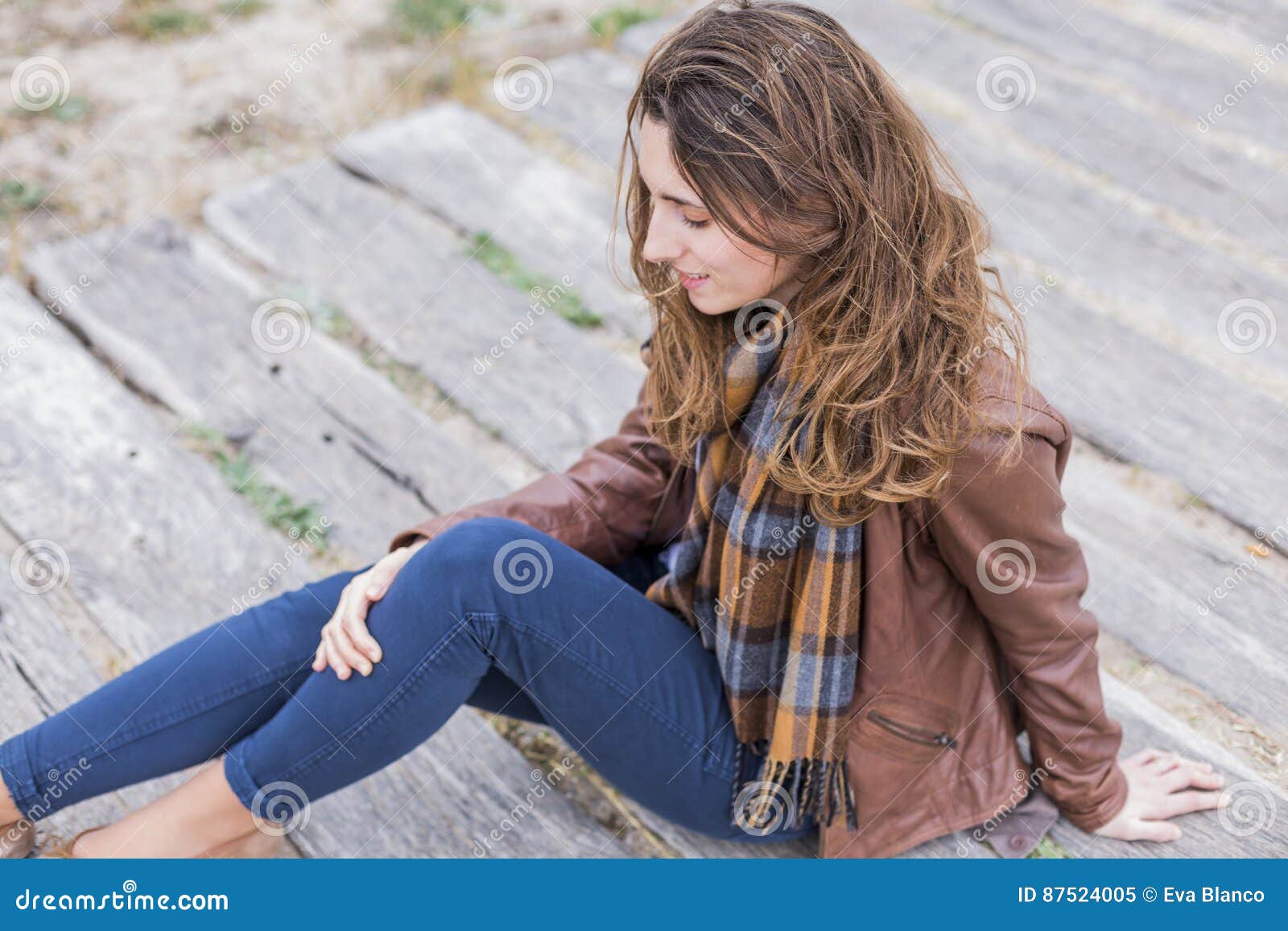 outdoors portrait of a young woman with brown jacket, jeans and