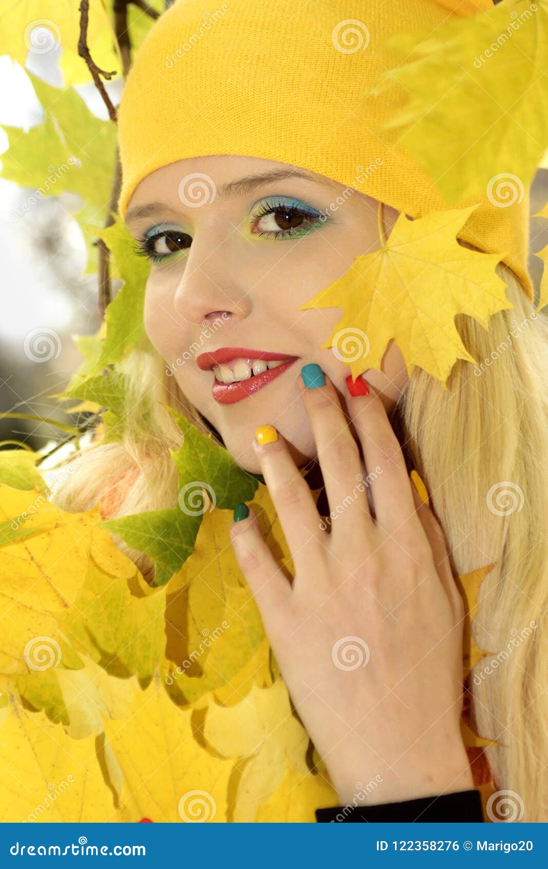 Outono dourado da composição e do tratamento de mãos. Menina loura bonita nova com cabelo longo com outono dourado colorido da composição e do tratamento de mãos