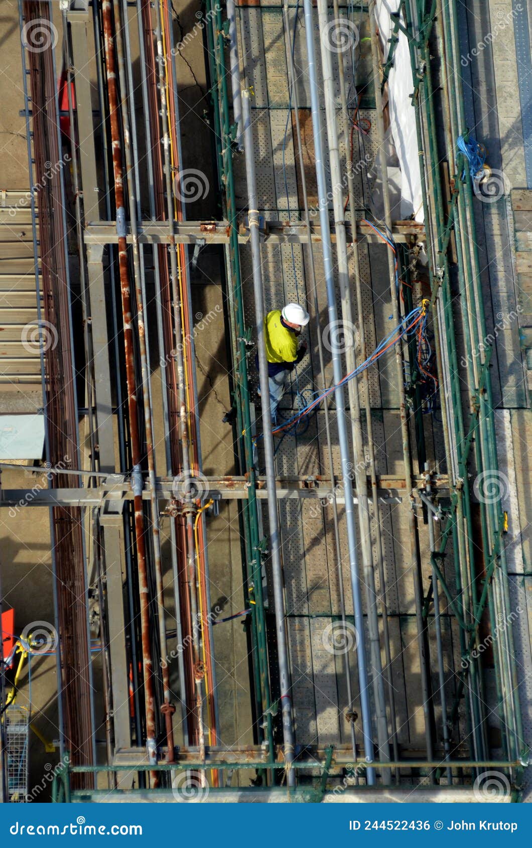 Overhead View of a Construction Worker Amongst Pipes and Scaffolding
