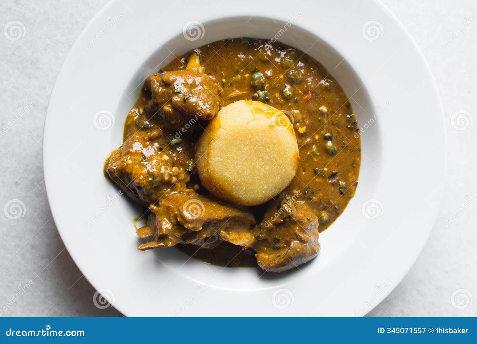 overhead view of nigerian ogbono soup and eba on a white plate