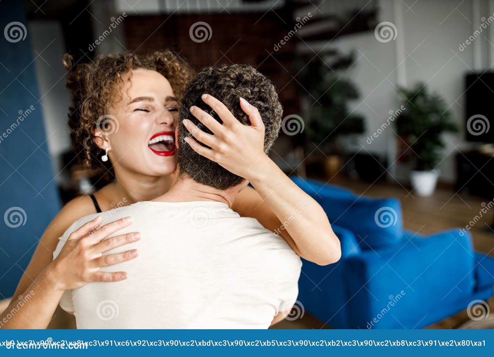 Overjoyed Happy Young Wife Hugging Her Husband Standing At Home