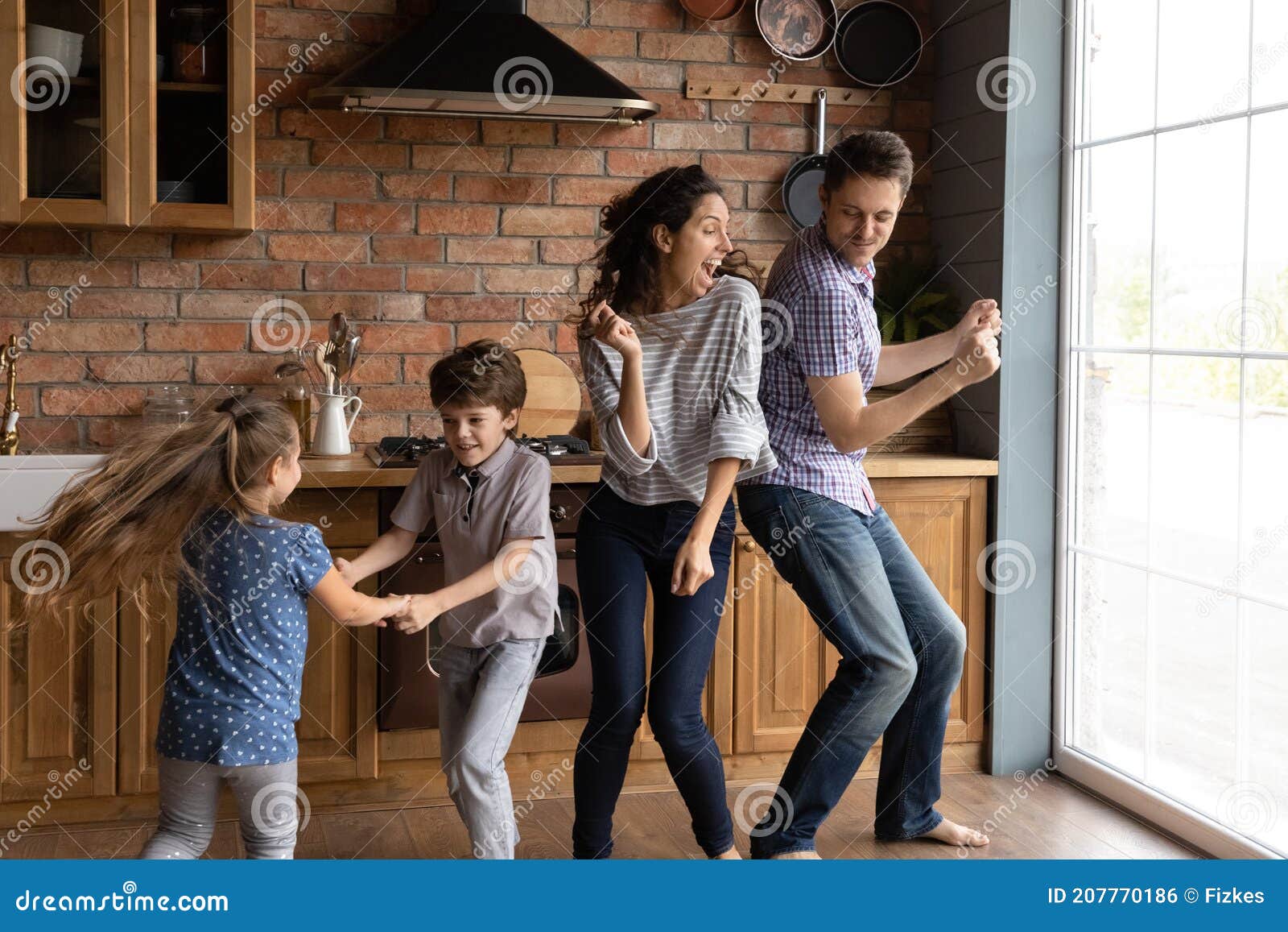 overjoyed young family with kids dance in kitchen